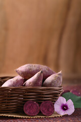 Organic purple sweet potatoes in basket with wooden background