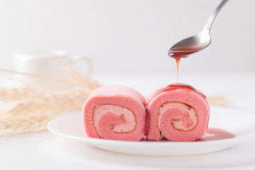 Pink strawberry roll cake or swiss roll with whipped cream and strawberry flavor eating with strawberry sauce