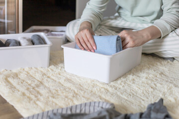Fototapeta na wymiar Female hands organizing storage of underwear socks t shirts use Marie Kondo's method. Perfectionist