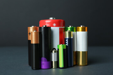 Different types of batteries on dark background - obrazy, fototapety, plakaty