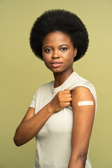 Happy african american woman with adhesive plaster on shoulder after getting coronavirus vaccine...