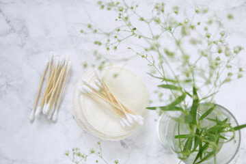 Organic wooden cotton buds,reusable tissue cosmetic sponges and gypsophila flowers on gray marble background.reasonable consumption.Zero waste.
