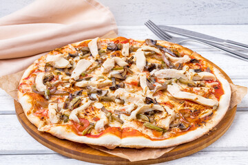 Pizza with chicken and mushrooms on white wooden table