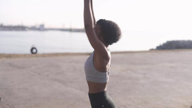 afro American young fitness personal trainer woman squat workout on the beach, positive daily routine concept