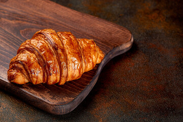 Croissant on wooden board dark background