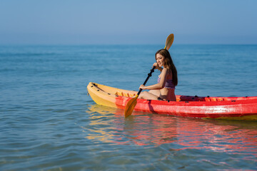 Fototapeta na wymiar woman in swimsuit paddling a kayak boat in sea