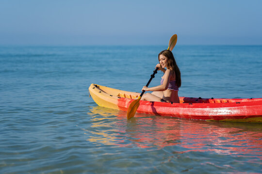 woman in swimsuit paddling a kayak boat in sea