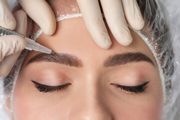 Young woman during procedure of permanent eyebrow makeup, closeup - obrazy, fototapety, plakaty