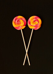 Two lollipops on a stick on a black background