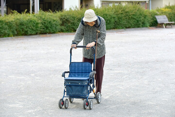 シルバーカーを押して散歩をする高齢者の女性