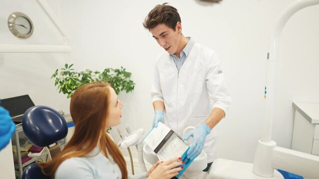 Professional dentist or orthodontist showing aligners or kappa for teeth alignment to female patient