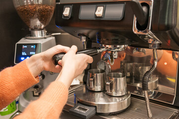 Women's hands put a tablet of ground coffee beans in the coffee machine