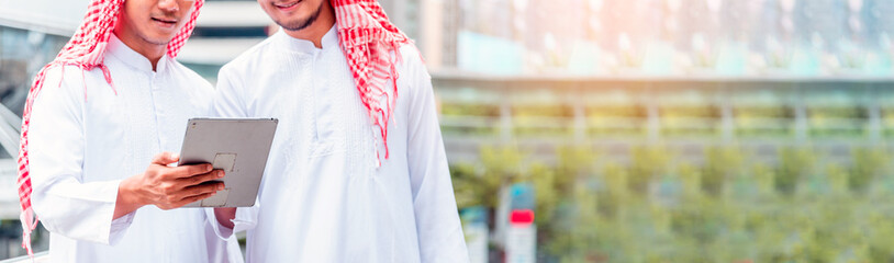 Banner Arab team hold digital tablet uae union teamwork people. Panorama arab group of people using smart tablet discuss modern muslim UAE city. Asian people smile teams meeting with copy space.
