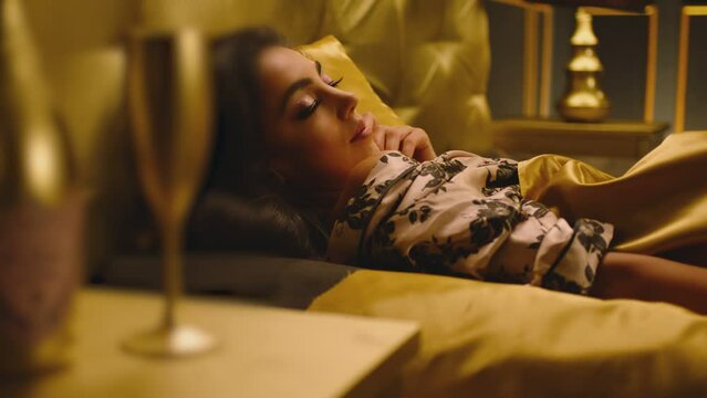 Beautiful Young Woman Sleeping Dreaming and Flirting in Bed . Female model resting lying asleep inside luxury golden bedroom . Golden room in hotel , house . Shot on ARRI cinema camera in slow motion
