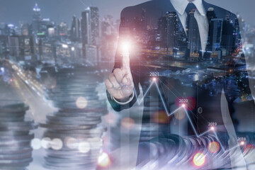 Fototapeta premium Double exposure of businessman and financial analyst using finger touch on abstract business chart bars and achieve exceptional financial results on cityscape background. Trade concept.