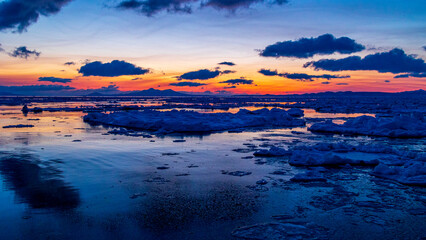 Fototapeta na wymiar 流氷の浮かぶ冬の根室海峡　日の出前の空と国後島