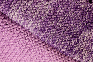 Macro abstract texture background of hand-knitted yarn wash cloths in a simple garter stitch, in varying shades of purple, pink and white