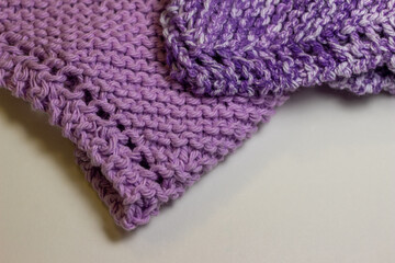 Macro abstract texture background of hand-knitted yarn wash cloths in a simple garter stitch, in varying shades of purple, pink and white