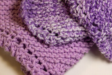 Macro abstract texture background of hand-knitted yarn wash cloths in a simple garter stitch, in varying shades of purple, pink and white