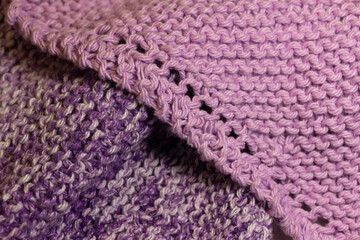 Macro abstract texture background of hand-knitted yarn wash cloths in a simple garter stitch, in varying shades of purple, pink and white