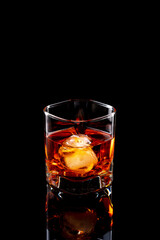 Scotch whiskey in glass with natural ice on black background.