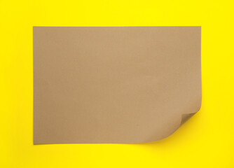 Sheet of brown paper on yellow background, top view