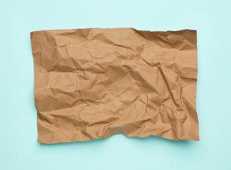 Sheet of crumpled brown paper on light blue background, top view