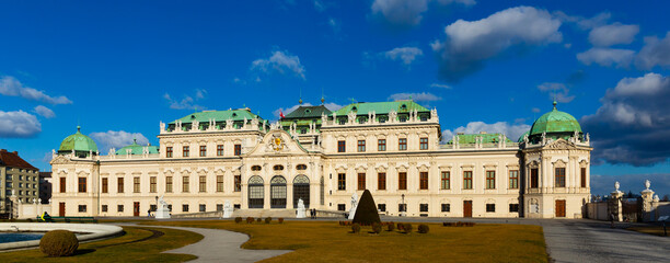 Obraz premium Scenic view of main facade and entrance of baroque building of upper Belvedere palace with large staircase and various sculptures on sunny day, Vienna, Austria
