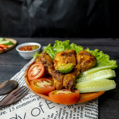 Grilled chicken with soy sauce and garnish with cucumber, tomato, lettuce, and chili