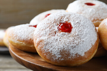Delicious donuts with jelly and powdered sugar on wooden pastry stand, closeup