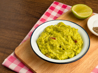 Fresh guacamole in a bowl on a wooden cutting board