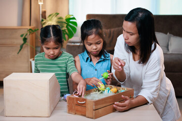 Asian mother and her daughters are decorating easter eggs preparing for Easter at home. Happy...