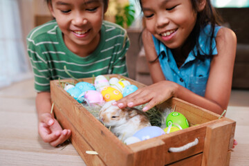 Asian siblings children are playing with baby bunny and decorating easter eggs preparing for Easter...
