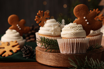 Different beautiful Christmas cupcakes and fir branches on wooden table. Space for text