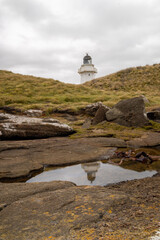 lighthouse reflecting in a rock pool