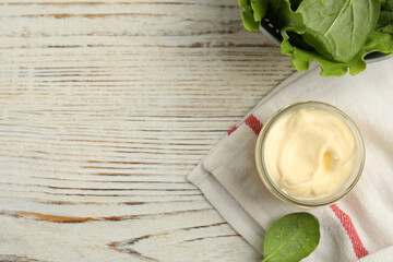 Jar of delicious mayonnaise and fresh spinach on white wooden table, flat lay. Space for text