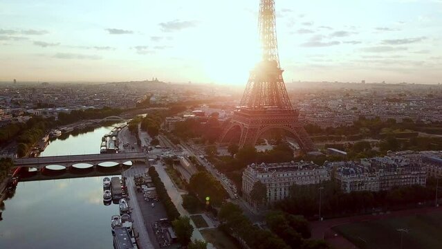 Aerial moving along and facing the I&eacute;na bridge then Eiffel Tower, at sunrise, over seine river. Close, sun facing.