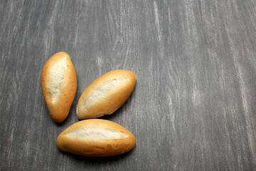 Obraz premium Fresh, delicious, hot and freshly made Mexican, French, bolilllo, white bread, loaf on a gray wooden table. Inexpensive food made with wheat flour 