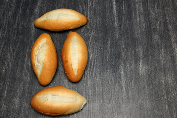 Obraz premium Fresh, delicious, hot and freshly made Mexican, French, bolilllo, white bread, loaf on a gray wooden table. Inexpensive food made with wheat flour 