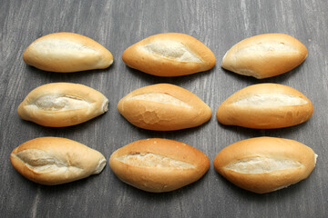 Fresh, delicious, hot and freshly made Mexican, French, bolilllo, white bread, loaf on a gray wooden table. Inexpensive food made with wheat flour
