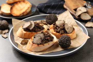 Delicious bruschettas with truffle sauce on grey table
