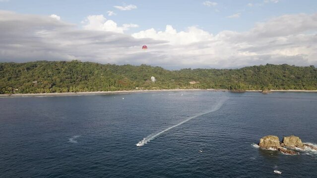 Parasailing off Manuel Antonio Beach on the beautiful Central Pacific Coast in Costa Rica. Panning aerial