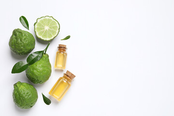 Glass bottles of bergamot essential oil and fresh fruits on white background, flat lay. Space for...