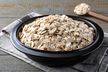 Bowl of oatmeal and spoon on wooden table, closeup
