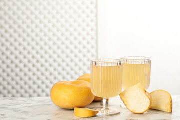 Glasses of freshly made turnip juice on white marble table, space for text