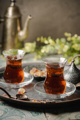 Turkish tea in traditional glass on tray closeup, tile background