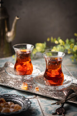 Turkish tea in traditional glass on tray closeup, tile background