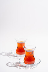 Turkish tea in traditional glass closeup on white background with bright shadows