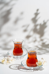 Turkish tea in traditional glass closeup on white background with bright shadows
