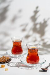 Turkish tea in traditional glass closeup on white background with bright shadows